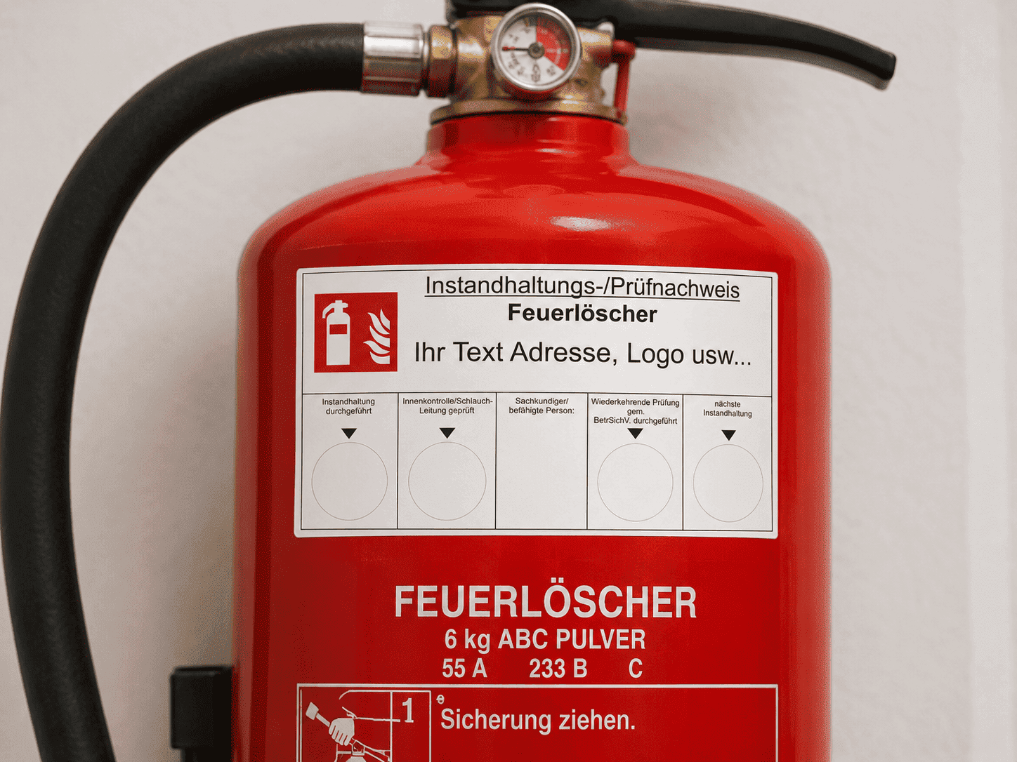 Korrekte Anbringung eines Wartungsaufklebers an einem Feuerlöscher gemäß DIN 14406-4 durch JK-Druckshop